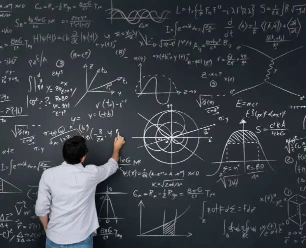 Photo of Physics teacher writing math equations on a blackboard