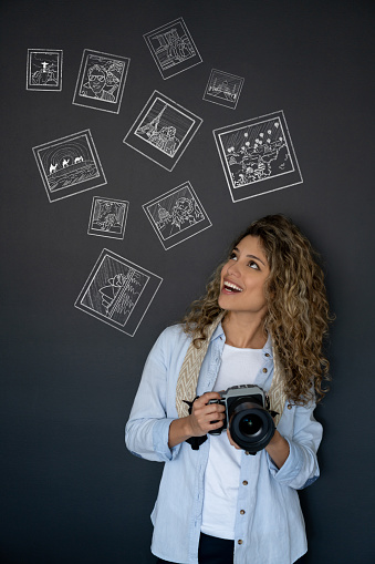 Conceptual image of a female traveler taking photos while traveling and holding a camera while smiling