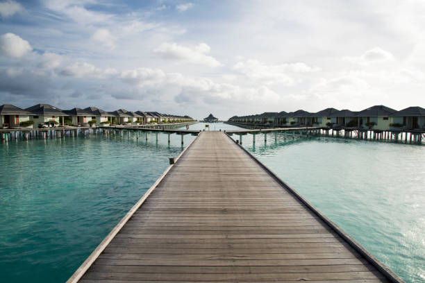 Maldives Water Bungalows A wooden jetty over calm water to a row of waterbungalows in a sunny tropical climate. Taken in the Maldives. water bungalow maldives stock pictures, royalty-free photos & images