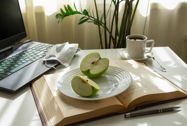 istock A workplace with a computer, an open book, an apple, a medical mask and a cup of coffee. 1220613437