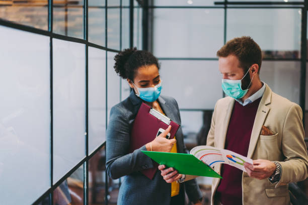 Business people wearing protective face masks at work during COVID-19 pandemic Businesspeople wearing masks in the office for illness prevention during COVID-19 pandemic epidemiology photos stock pictures, royalty-free photos & images