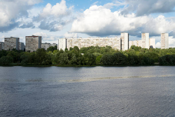 istock Wide river, shore with forest and multi-storey houses. 1220617443