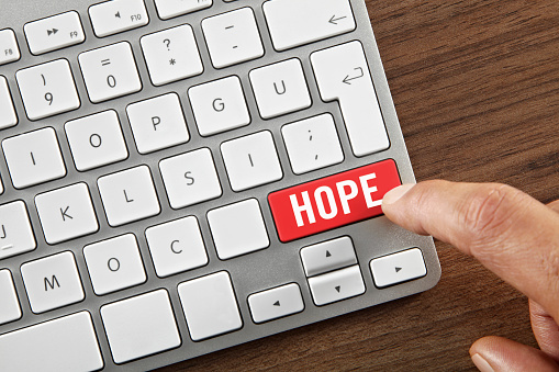 Man pushing 'Hope” button on computer keyboard.