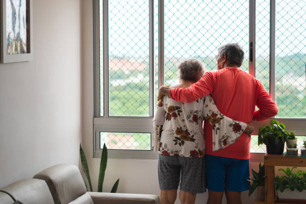 istock Senior people looking through the window at home 1220621330