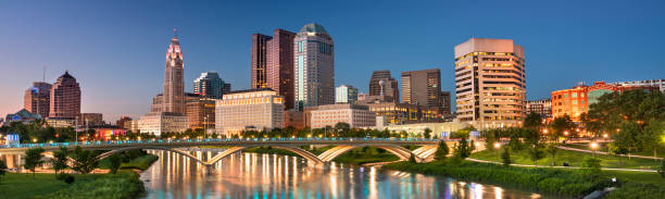 Downtown city skyline view of Columbus Ohio USA at night Downtown panoramic cityscape looking over the Scioto River and the Discovery Bridge along the Riverfront Park in the city of Columbus Ohio USA columbus stock pictures, royalty-free photos & images