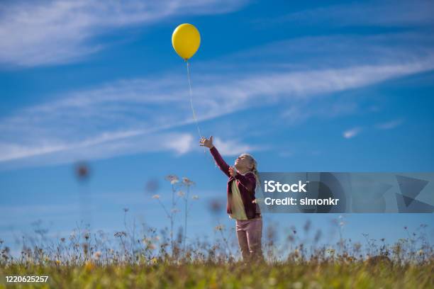 Girl Releasing Balloon Against Blue Sky Stock Photo - Download Image Now - Balloon, Releasing, Child