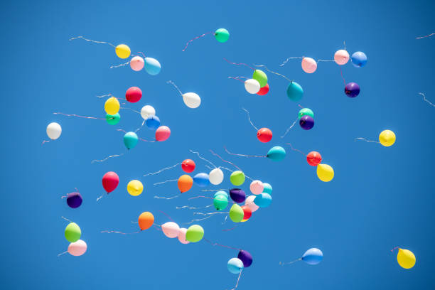 istock Multicoloured balloons flying against blue sky 1220625263