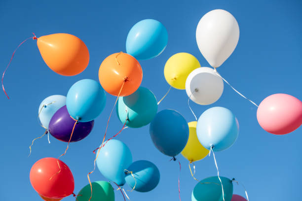 istock Multicoloured balloons flying against blue sky 1220625283