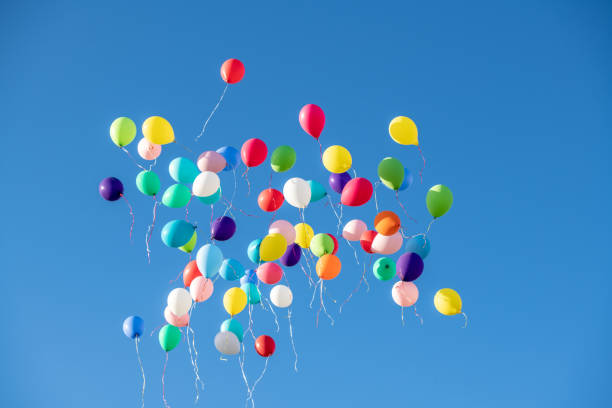 istock Multicoloured balloons flying against blue sky 1220625292