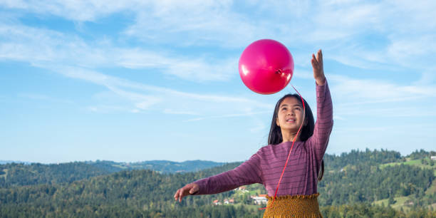 Balloons float up against a cloudy sky.