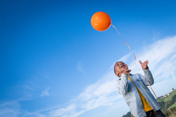 istock Boy releasing balloon in blue sky 1220625306