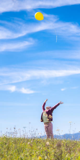 istock Girl releasing balloon against blue sky 1220625310