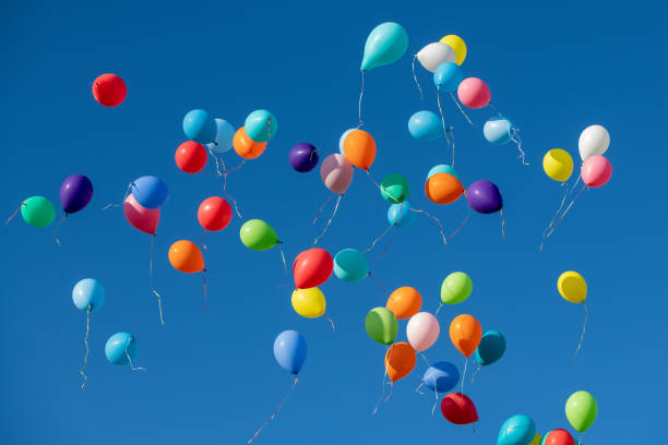 istock Multicoloured balloons flying against blue sky 1220625316