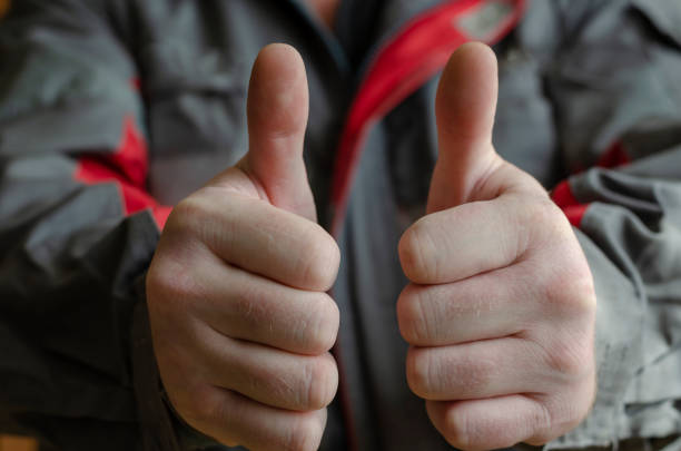 un homme montre deux gestes avec son pouce vers le haut. - thumbs up repairman human thumb electrician photos et images de collection