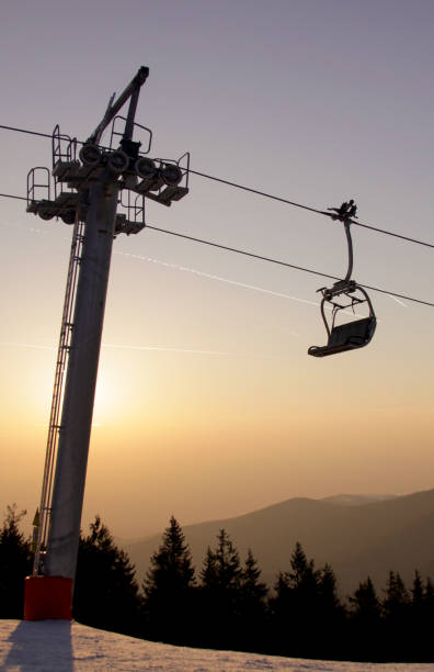 Ski lift chair on ski slope at sunset stock photo