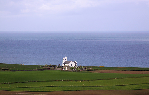 White church on the coast in Ireland next to ocean
