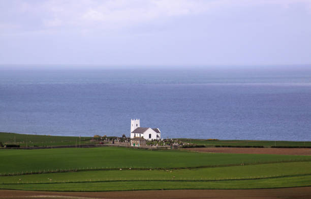 White church on the coast in Ireland next to ocean stock photo