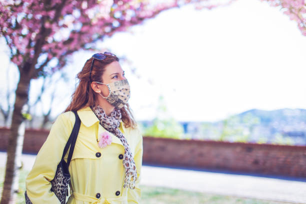 istock Young woman in mask walking at park during Sakura 1220633786