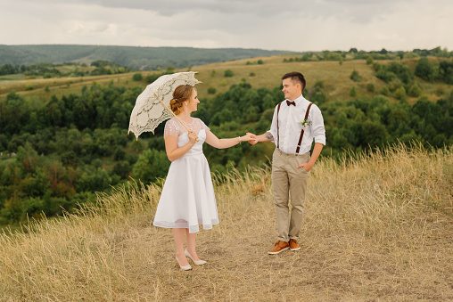 The groom holds the bride by the hand at wedding against the backdrop of a beautiful landscape