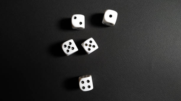 istock White and black dice disorganized over black background. 1220637516