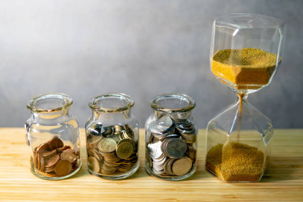 coin jars and hourglass. save money for retirement - stock market data insurance savings finance imagens e fotografias de stock