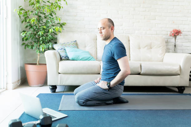 istock Man doing yoga from a laptop computer at home 1220639939