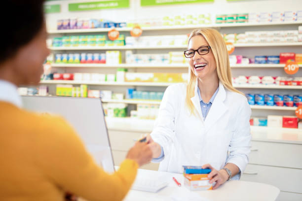 istock Happy pharmacist receiving a credit card from a client. 1220640301