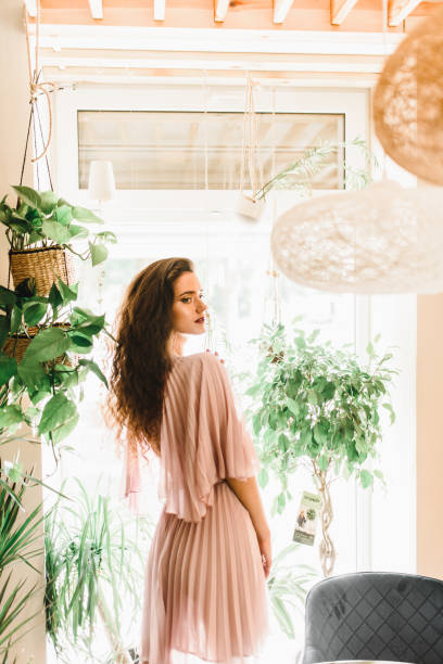 istock Professional model is standing opposite to window and looking to the right side. Natural beauty women with long wavy hair. 1220640422