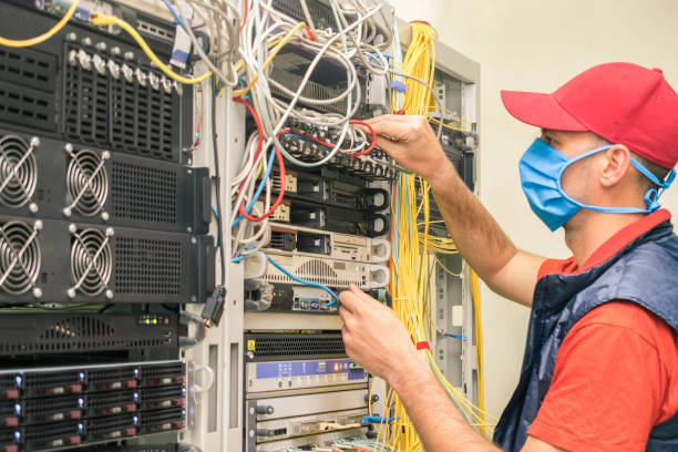 istock A man in a red cap works in a datacenter. A technical employee maintains computer equipment. A technician in a medical mask switches wires in the server room. 1220642174
