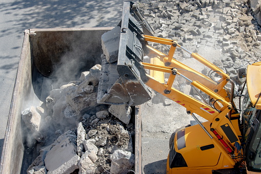 Bulldozer loader uploading concrete debris into dump truck