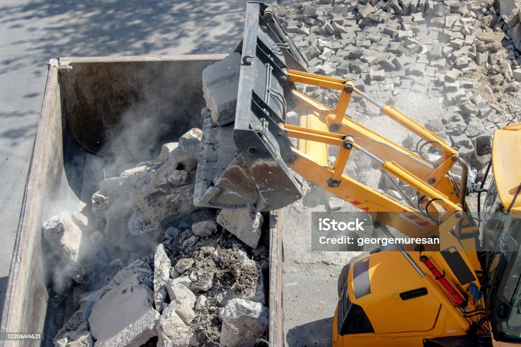 Bulldozer loader uploading concrete debris into dump truck Bulldozer loader uploading concrete debris into dump truck at construction site Construction Industry Stock Photo
