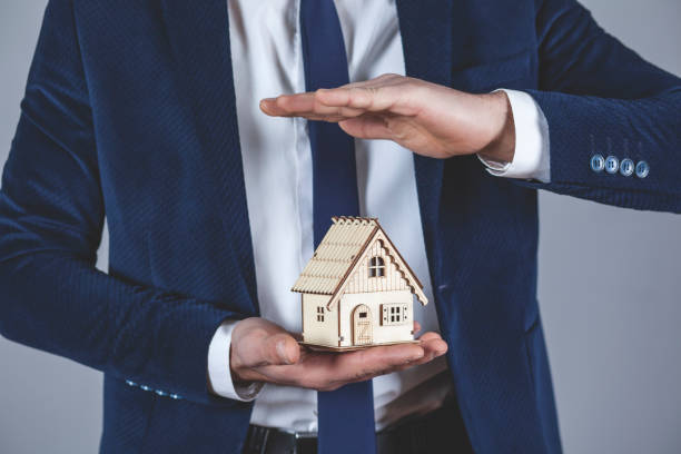 istock man hand holding wooden house model 1220645327
