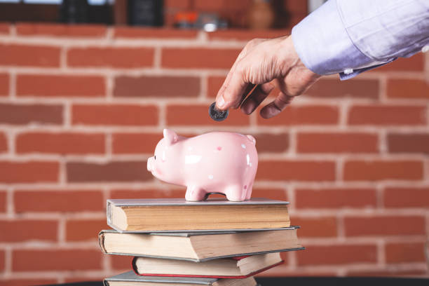 istock man hand coin with piggy bank on book 1220645371