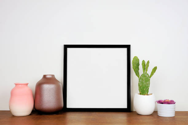 istock Mock up black frame with home decor and potted plants on a wood shelf with white wall 1220645522