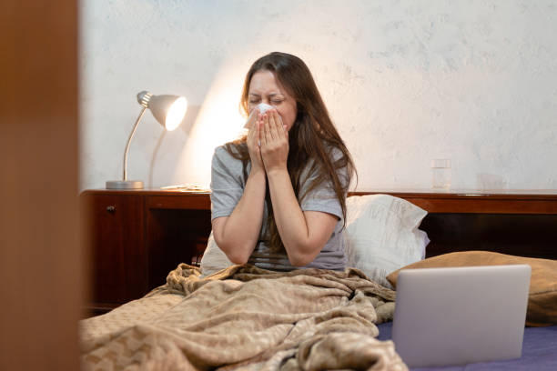 istock Woman in her bed trying to perform her tasks during severe flu. Sick concept 1220647549