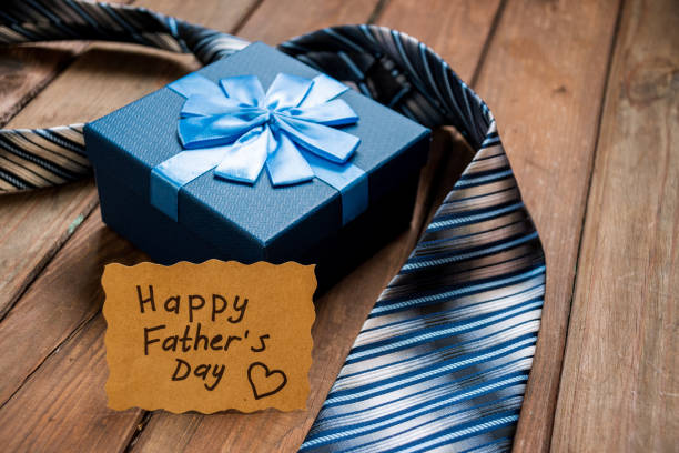 istock Happy Fathers Day gift box with tie on a rustic wood background. 1220648402