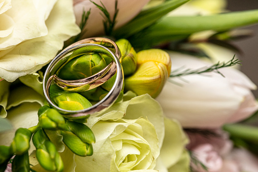 Wedding rings placed on a bride's bouquet consisting of colorful roses.