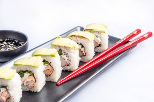 sushi roll with avocado wrap, grilled salmon, philadelphia cheese and green onions black container and red chopsticks - fine dining grilled spring onion healthy lifestyle imagens e fotografias de stock