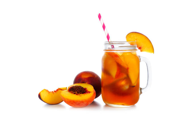 summer peach iced tea in a mason jar glass with cut fruit isolated on white - chá gelado imagens e fotografias de stock