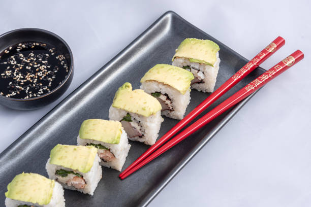 sushi roll with avocado wrap, grilled salmon, philadelphia cheese and green onions black container and red chopsticks - fine dining grilled spring onion healthy lifestyle imagens e fotografias de stock