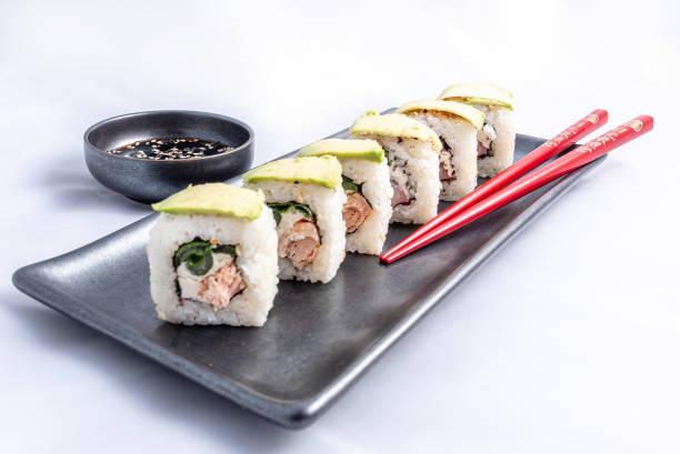 sushi roll with avocado wrap, grilled salmon, philadelphia cheese and green onions black container and red chopsticks - fine dining grilled spring onion healthy lifestyle imagens e fotografias de stock