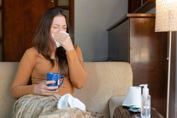 istock Woman sitting on the couch with a cold. Feeling Sick Concept 1220649940