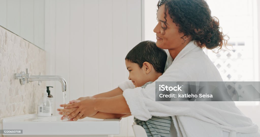 We make sure we wash our hands regularly Cropped shot a mother helping her adorable young son wash his hands in the bathroom at home Washing Hands Stock Photo