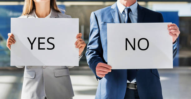 istock Business people standing while holding white YES or NO placard 1220652041