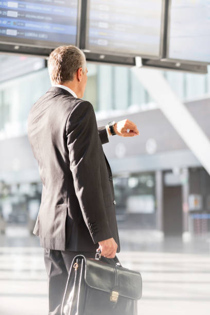 istock Businessman looking on his watch while waiting for boarding in airport 1220653549