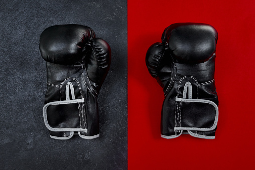 High angle shot of a pair of boxing gloves placed together on top of a multi coloured background inside of a studio