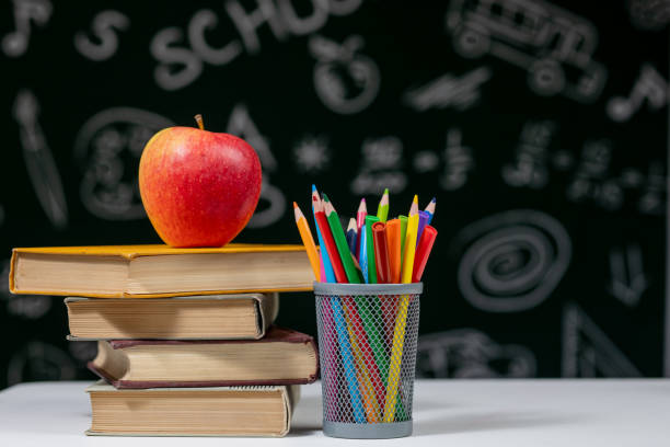istock Back to school background with books, pencils and apple on white table. 1220659436