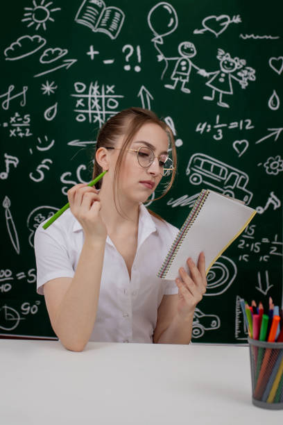 istock Young teacher is sitting near blackboard in classroom 1220667233