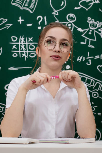 istock Young teacher is sitting near blackboard in classroom 1220667772