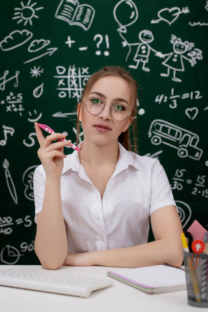 istock Young teacher is sitting near blackboard in classroom 1220667821